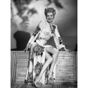 Smiling Betty Grable Sitting on Wooden Structure