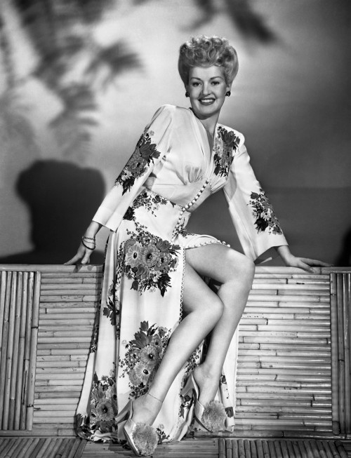 Smiling Betty Grable Sitting on Wooden Structure